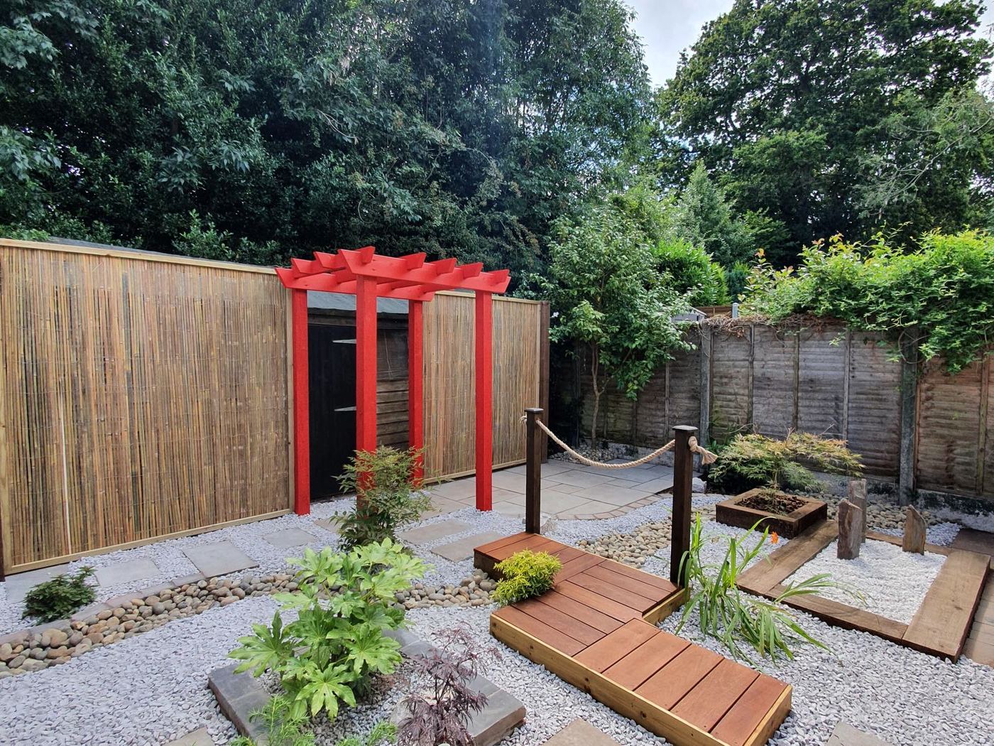 After: Finished Japanese Zen garden with red pergola, decking bridge and pebble stream
